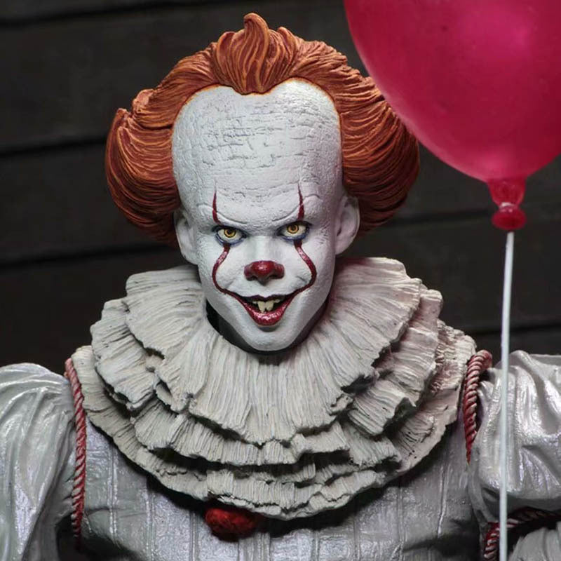 Clown with red hair and white face holding a red balloon against a dark background