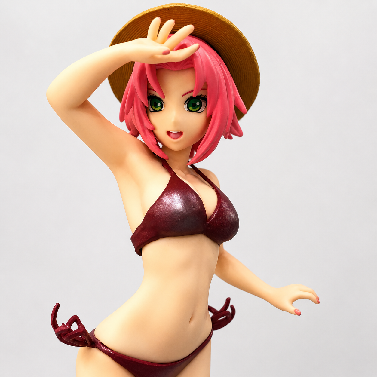Figurine of a character with pink hair and a straw hat, wearing a red bikini against a light gray background.